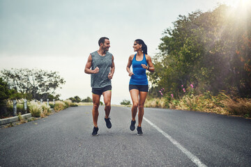 Couple, road and smile with running for fitness for training, support and love in California. Workout, exercise and people with jogging for health or wellness and wellbeing in morning with lens flare