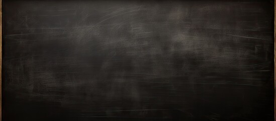 A dark blackboard background with the textured appearance of chalk creating a perfect copy space image for a school education themed learning board concept