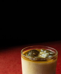 Cocktail with cold coffee and liquor in glass on red and black background 