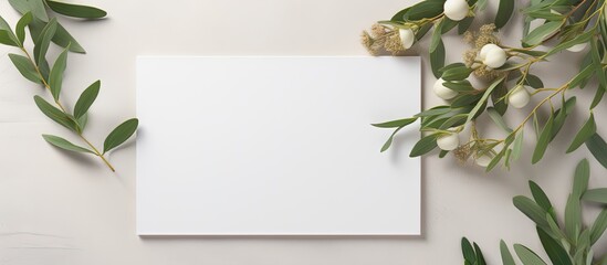 A feminine Mediterranean top view of a summer wedding stationery mock up scene with a blank greeting card a craft paper envelope and green branches on a white table background This copy space image s