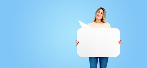 Smiling woman holding a mockup speech bubble on empty blue background