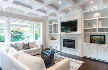 A photo of the living room in an elegant suburban home, featuring a coffered ceiling with beams and white cabinets for storage on each side of the fireplace. Created with Ai