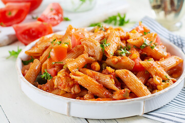 Classic italian pasta penne arrabbiata with vegetables on white wooden table. Penne pasta with sauce arrabbiata.