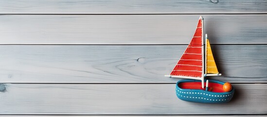 A flat lay copy space image featuring a toy sailing boat with an aircraft and dotted flip flops on a grey wooden surface