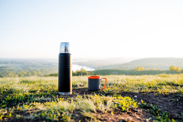 Enjoy a morning adventure with a thermos and mug overlooking a scenic landscape. Experience the...