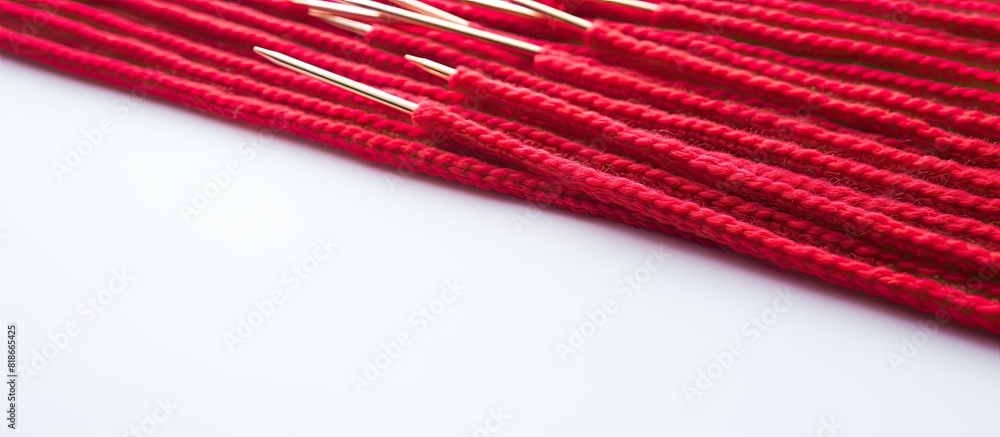 Poster a close up image of thin red patterned knitting needles being used to knit either sweaters or a scar