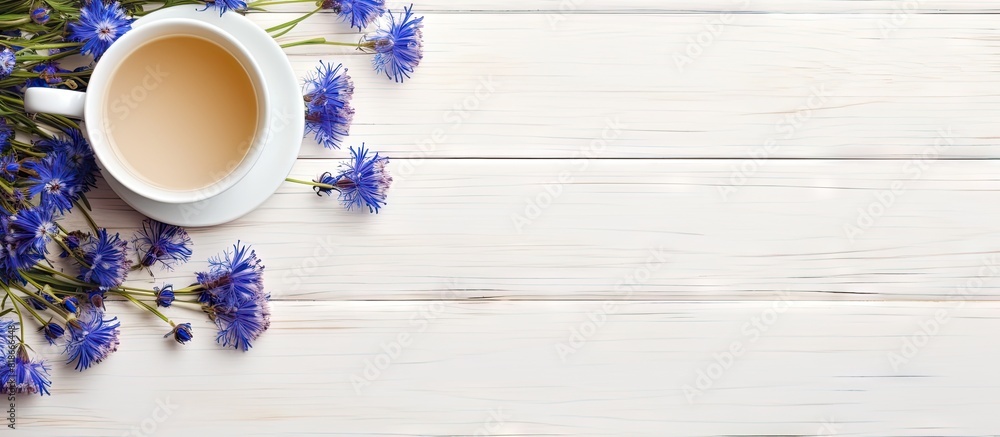 Poster Flat lay of a cup of tea and cornflowers on a white wooden table with ample copy space for adding text