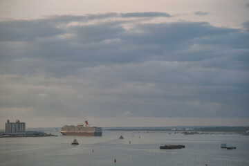 Luxury ocean liner cruiseship cruise ship Queen Victoria early morning arrival on Solent into Southampton port, Great Britain with maritime traffic and harbor infrastructure