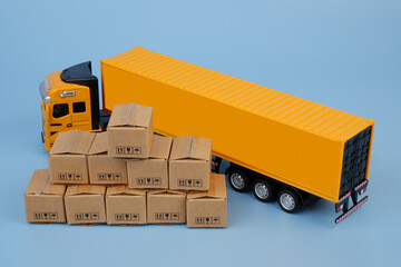 Yellow cargo truck and many shipping carton boxes on blue background. Shipping goods and cargo concept.	