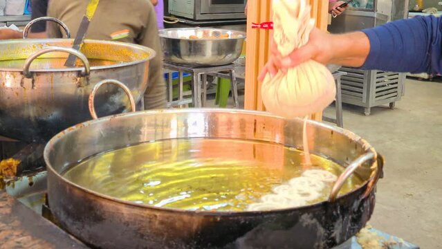 chef cook in a store making the sweet crispy jalebi dish a popular street food snack in India specially using celebrations like diwali, Dussehra and more