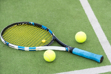 Tennis ball and racket on the ground of sunny outdoor grass tennis court. Summer, healthy lifestyle, sport and hobbies.