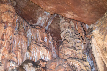 A cave with a lot of rock formations and stalactites hanging from the ceiling. Scene is mysterious...