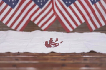 Fototapeta premium White banner features a child's handprint with American flags waving in the background for a creative and heartfelt Memorial Day tribute.