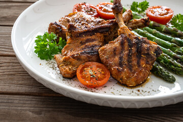 Lamb chops with bone and cooked green asparagus on wooden table
