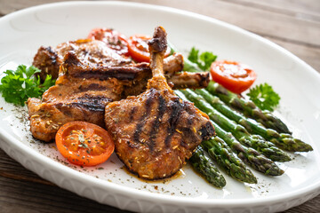 Lamb chops with bone and cooked green asparagus on wooden table
