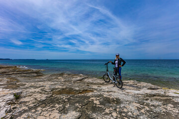 Fototapeta premium Cycling routes in Croatia woman in helmet riding electric bike on Adriatic Sea e-bike
