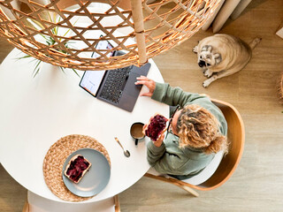 Top vertical view of woman in morning lifestyle having breakfast while use laptop to check emails...
