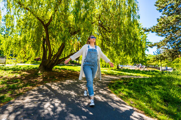 Spring walk - mid-adult beautiful woman walking in city park on sunny day
