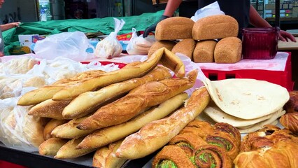 Seller of bread, baguette. Bakery on the Tel Aviv market, fresh baked goods. People buy pita in bags. Traditional Israeli flatbreads