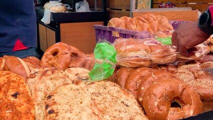 Seller of bread, baguette. Bakery on the Tel Aviv market, fresh baked goods. People buy pita in bags. Traditional Israeli flatbreads