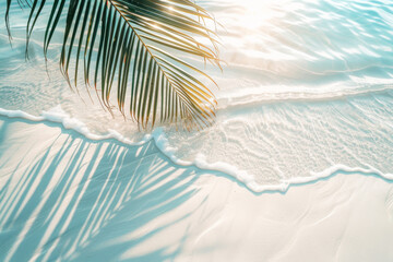 A palm tree is laying on the sand next to the ocean. The water is calm and the sun is shining brightly