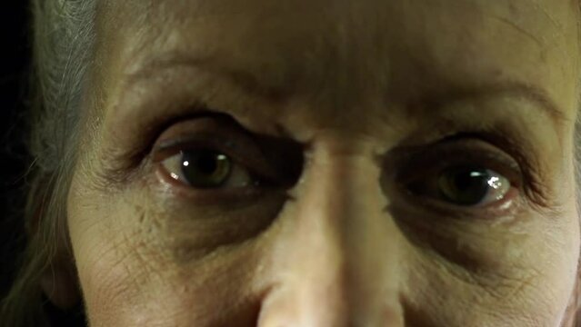 Closeup shot on the eyes of an old woman while she is talking to the camera, scene in a sci-fi movie