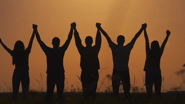 Success team hands up. business a team teamwork concept. group of people holding hands raised their hands up silhouette in nature sunset. motivational video for team business video lifestyle
