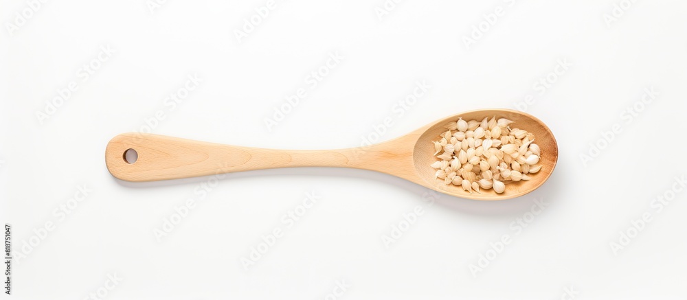 Poster copy space image of minced garlic in a wooden ladle on a white table background seen from the top