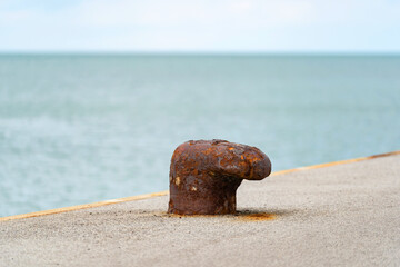 rusted bollard on concrete pier by the sea