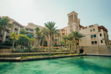 Clock tower standing tall amidst palm trees near a grand structure: Dubai, UAE