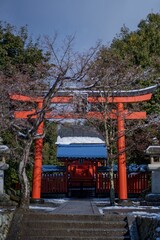 an orange tori gate with red pillars and snow on the ground