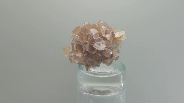 Closeup rotating shot of Aragonite rose on glass base against gray background