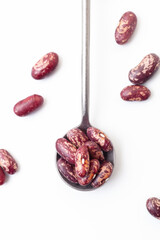 Dry grains of red and white beans in iron spoon on white background