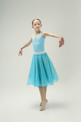 young teenage ballerina girl shows ballet steps in a photo studio