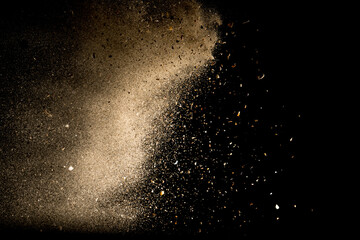 Yellow sand fly wave in the air. Golden sand explosion isolated on black background. Abstract sand...