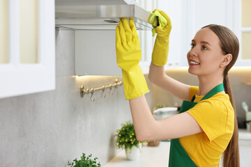 Woman cleaning kitchen hood with rag indoors