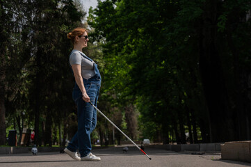 Blind pregnant woman crosses the street with the help of a tactile cane.