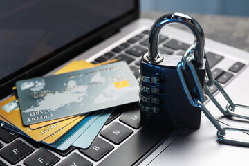 Cyber security. Metal combination padlock with chain and credit cards on laptop, closeup