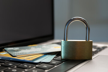 Cyber security. Metal padlock with chain and credit cards on laptop, closeup