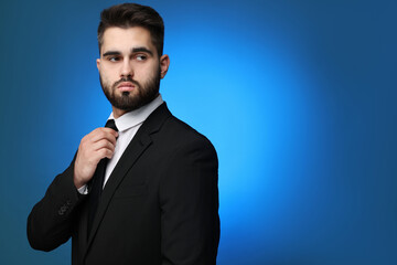 Handsome businessman in suit and necktie on blue background. Space for text
