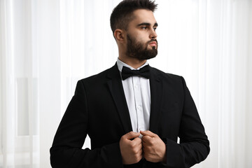 Portrait of handsome man in suit, shirt and bow tie indoors