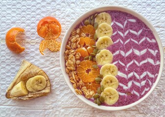 Berry smoothie bowl made from blueberry, blackberry and banana and yogurt, topped with seeds and almond, goji berry and shredded lemon skin	