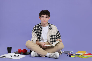 Portrait of student with notebook and stationery sitting on purple background