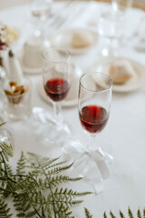 Glasses with bows and wine adorned with flowers on a table
