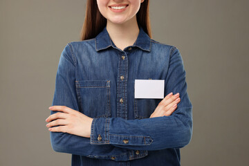Woman with blank badge on grey background, closeup