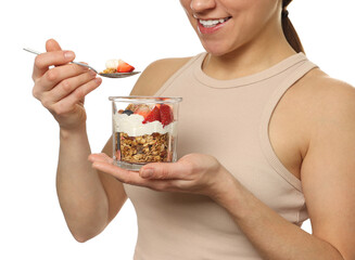 Happy woman eating tasty granola with fresh berries and yogurt on white background, closeup