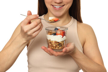 Happy woman eating tasty granola with fresh berries and yogurt on white background, closeup