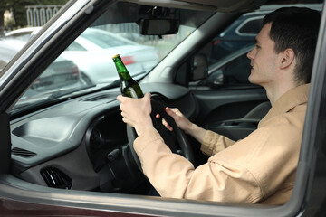 Man with bottle of beer driving car, view from outside. Don't drink and drive concept