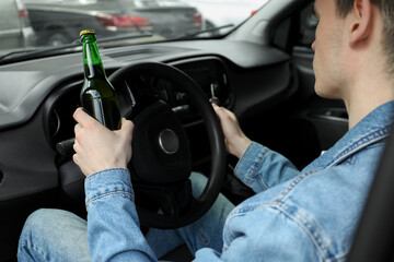 Man with bottle of beer driving car, closeup. Don't drink and drive concept