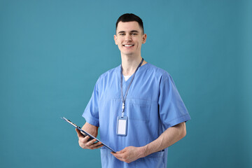 Portrait of smiling medical assistant with clipboard on light blue background